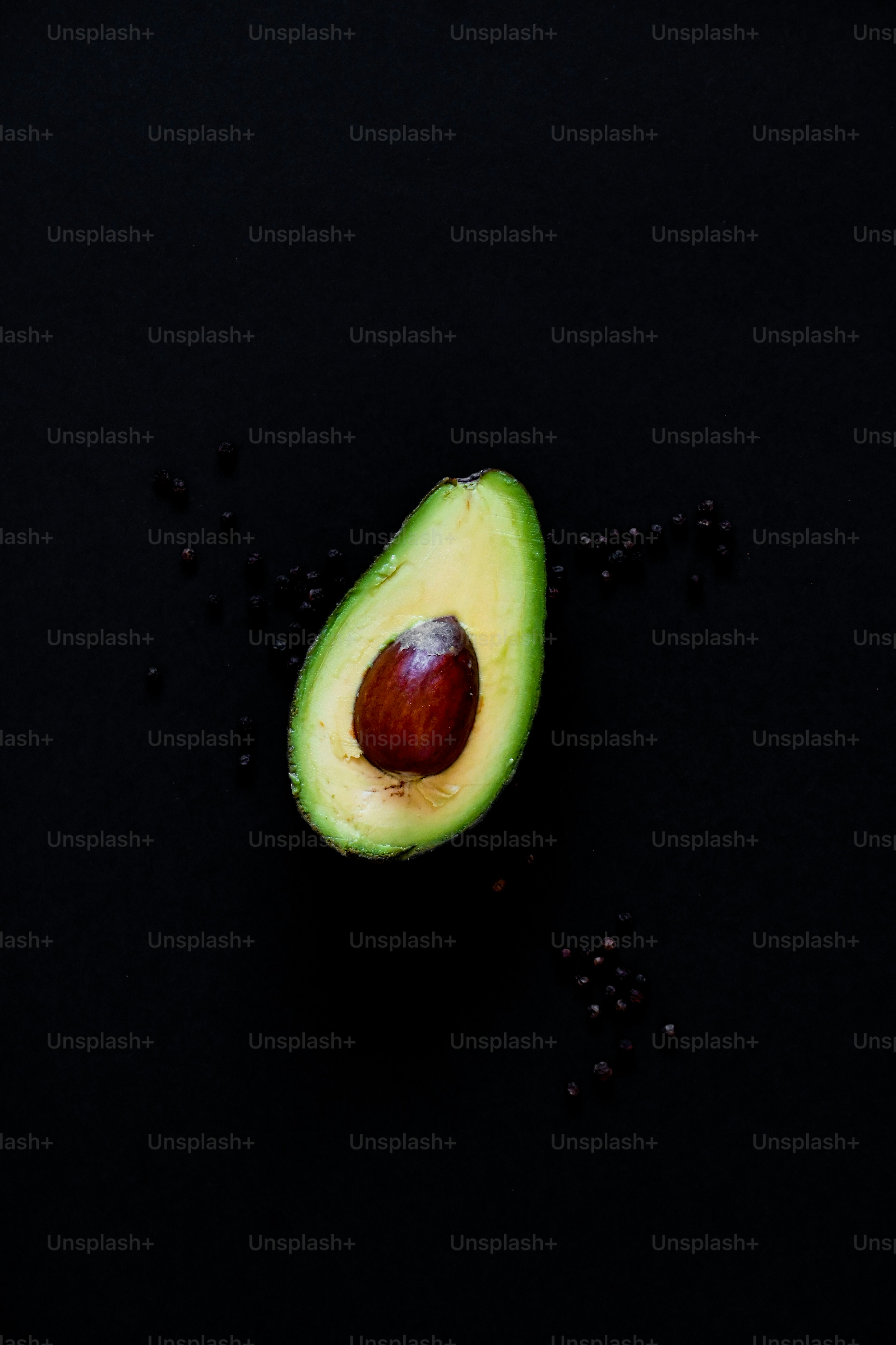 an avocado cut in half with seeds scattered around it