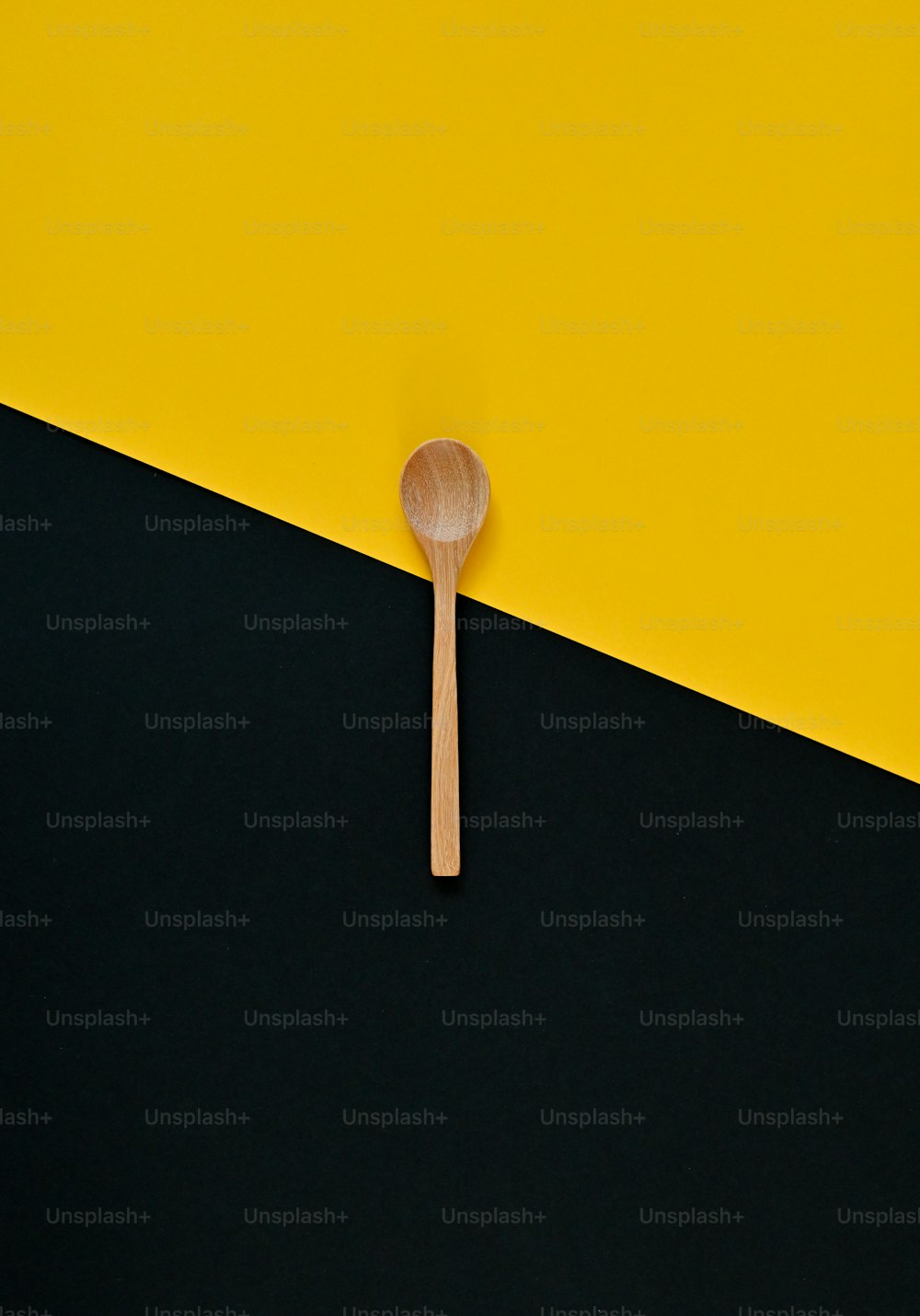 Una cuchara de madera sentada encima de una pared negra y amarilla