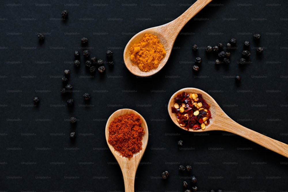 three wooden spoons filled with different types of spices