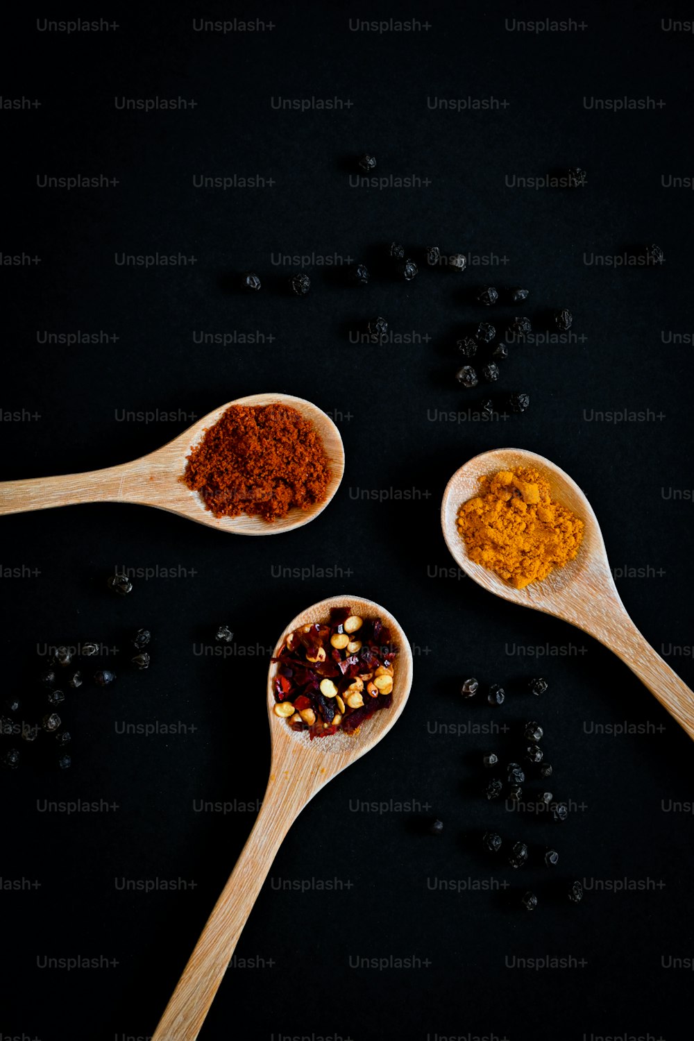 three wooden spoons filled with different types of spices