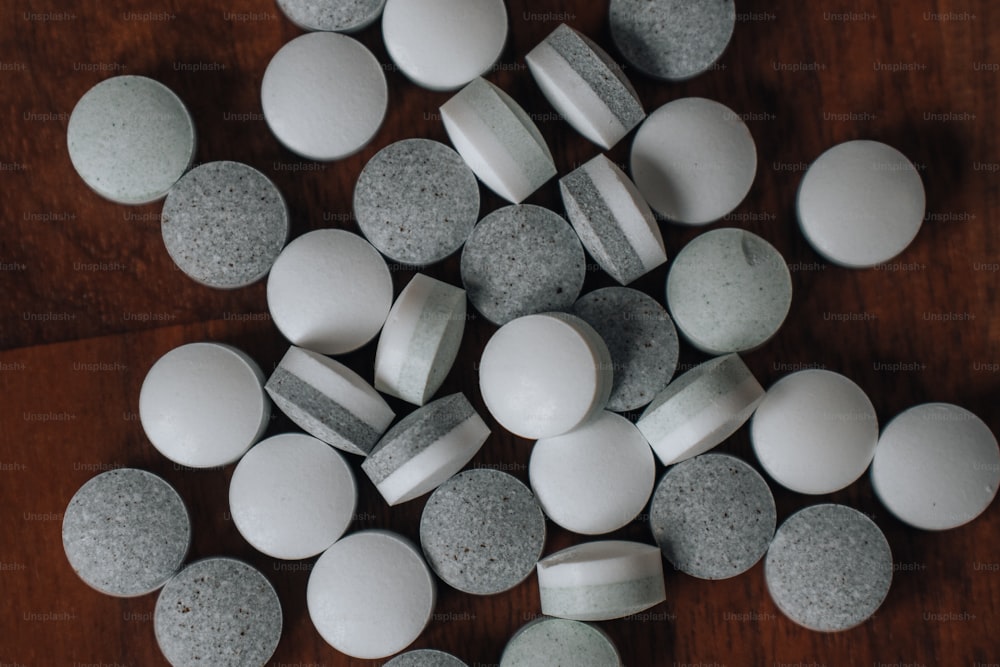 a wooden table topped with lots of white and grey pills