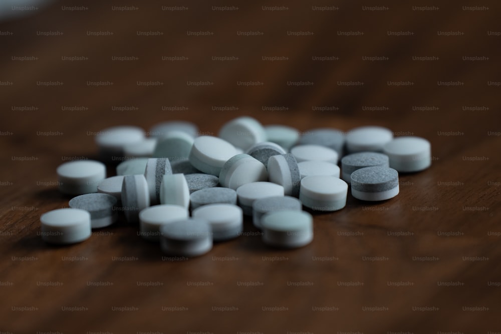 Un montón de pastillas sentadas encima de una mesa de madera