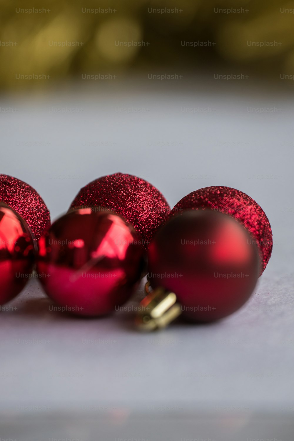 Tre ornamenti rossi lucidi su una superficie bianca