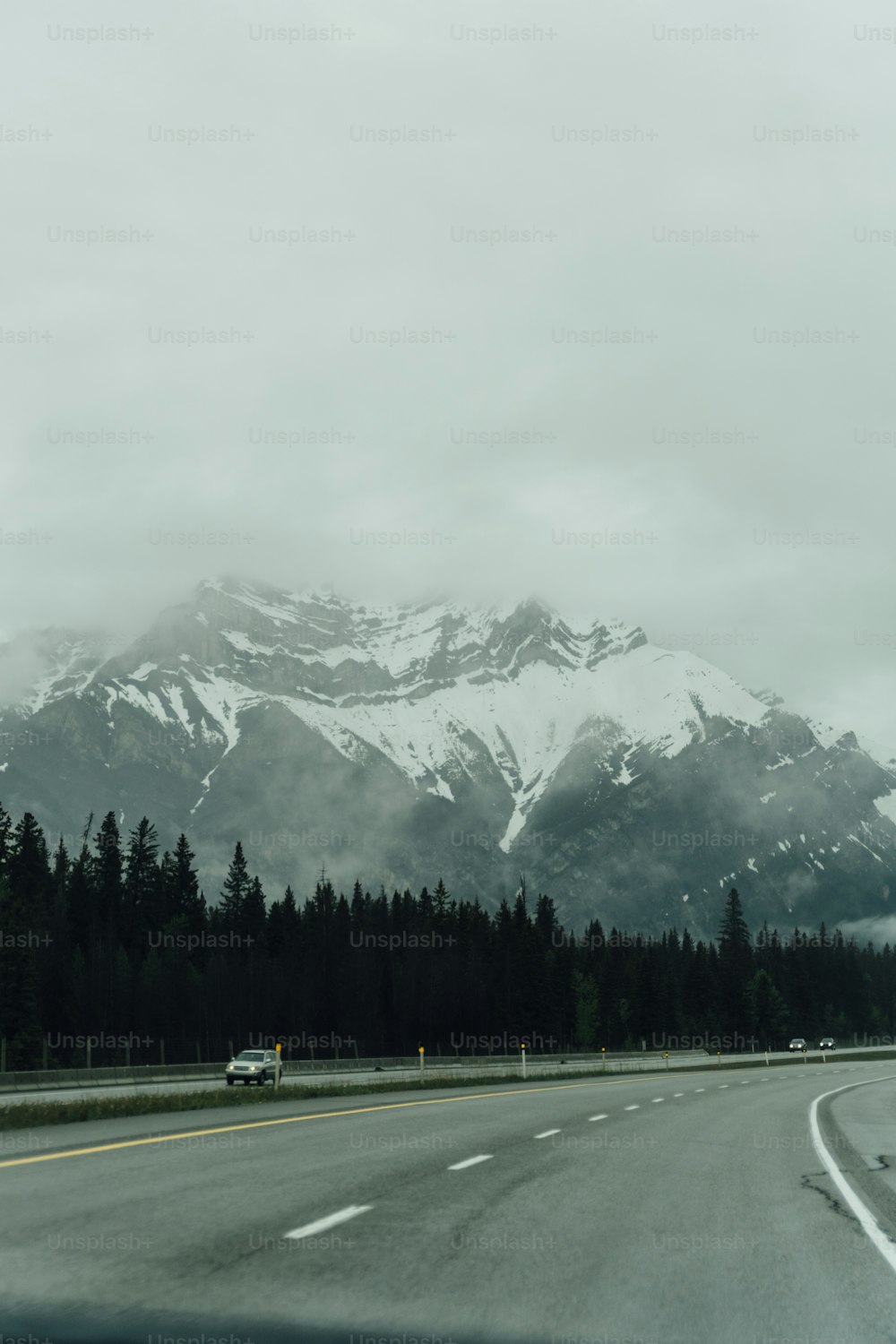 Un coche conduciendo por una carretera con una montaña en el fondo