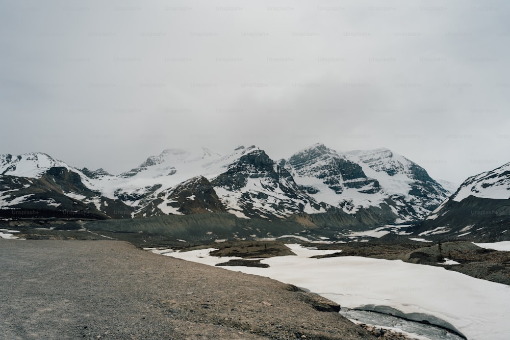 a snow covered mountain range with a road in the foreground