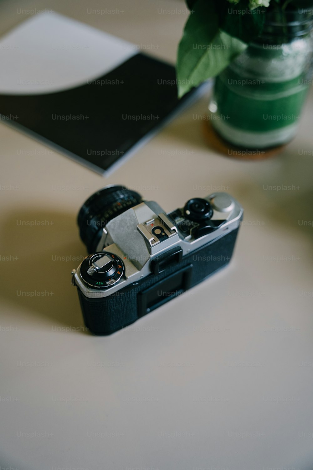 a camera sitting on top of a table next to a vase of flowers