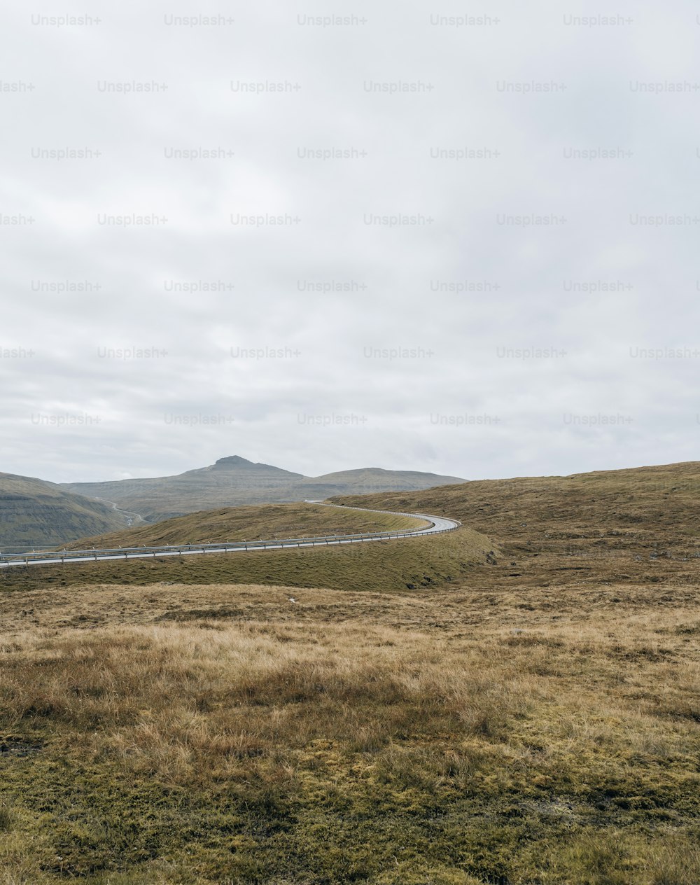 a grassy field with a road in the distance