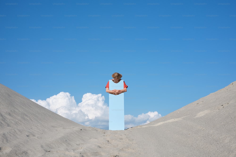 Una persona parada encima de un bloque azul en la arena
