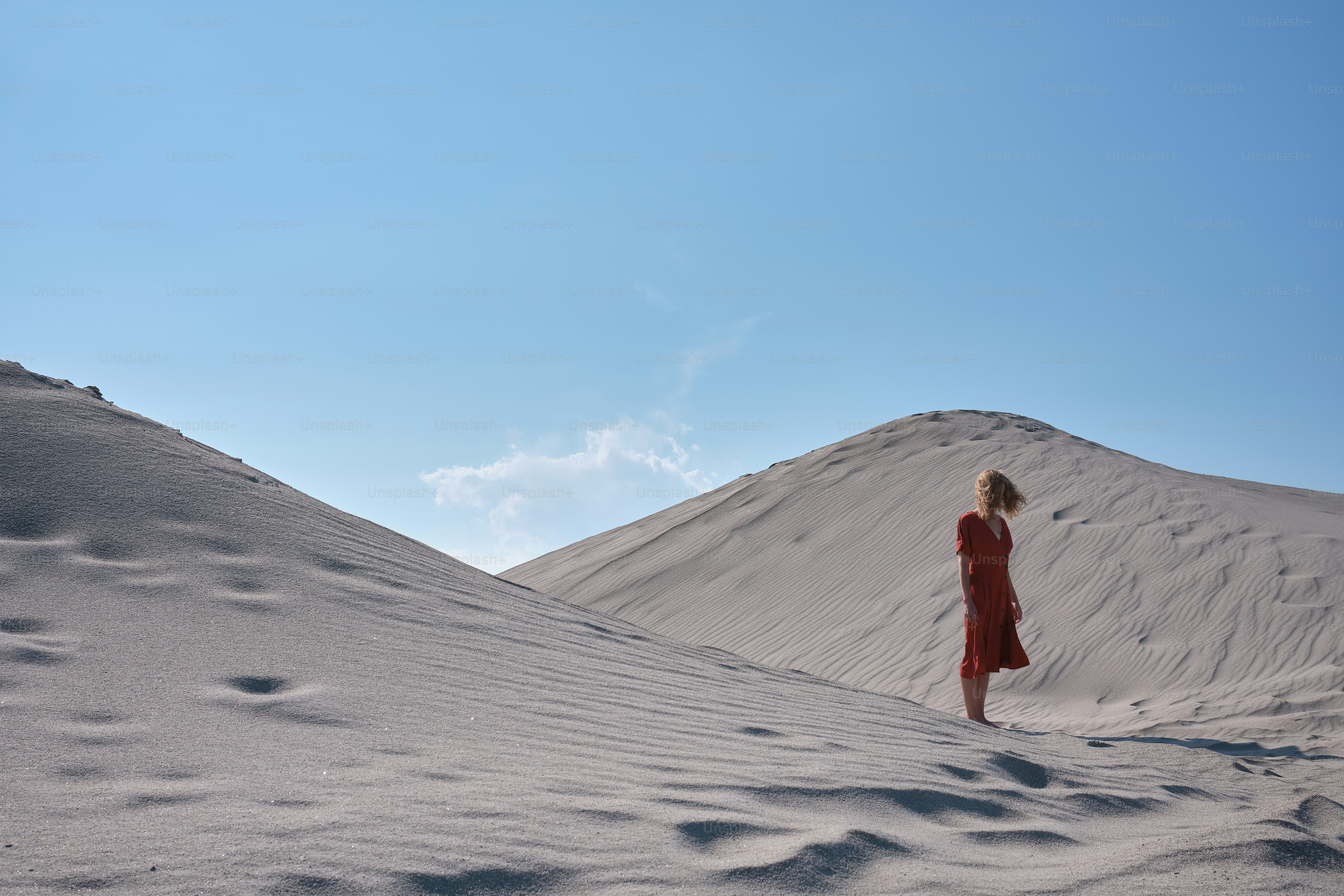 a woman in a red dress standing in the sand
