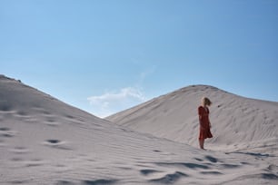 Eine Frau in einem roten Kleid steht im Sand