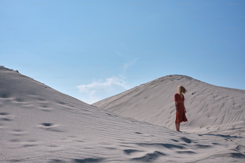 a woman in a red dress standing in the sand