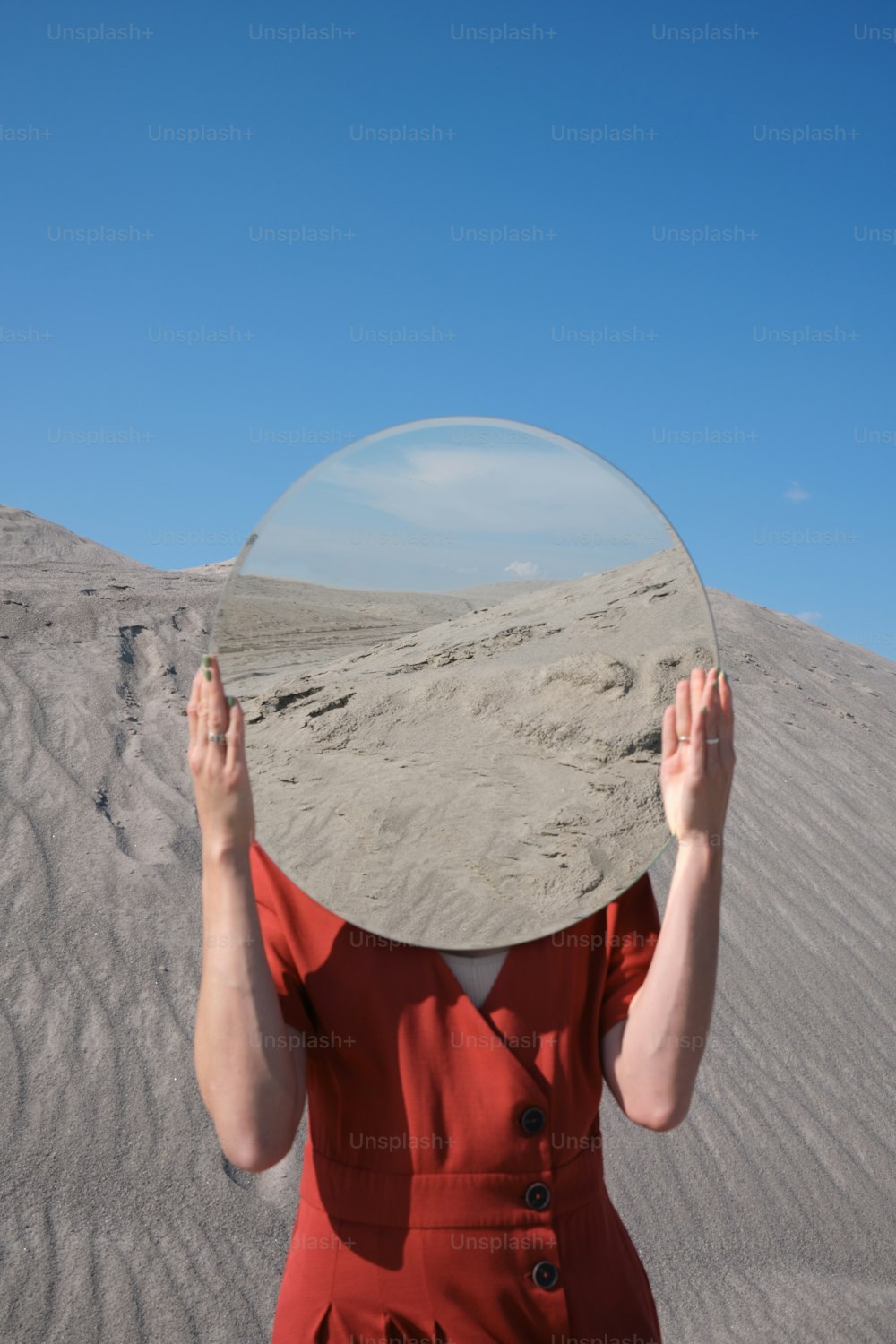 a woman in a red dress holding a mirror over her face