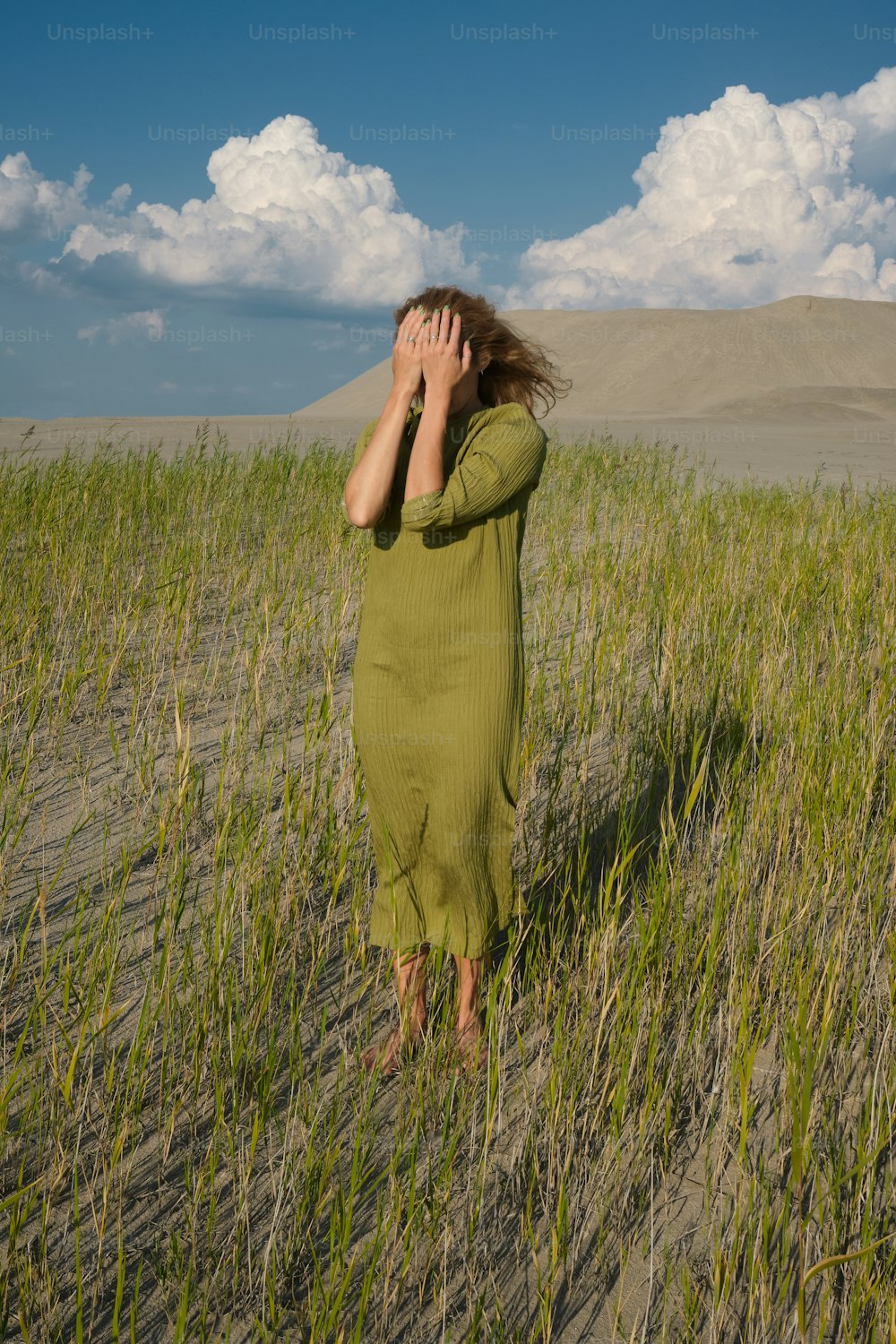 uma mulher caminhando por um campo de grama alta