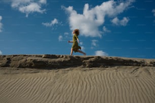 緑のドレスを着た女性が砂の中を走っている
