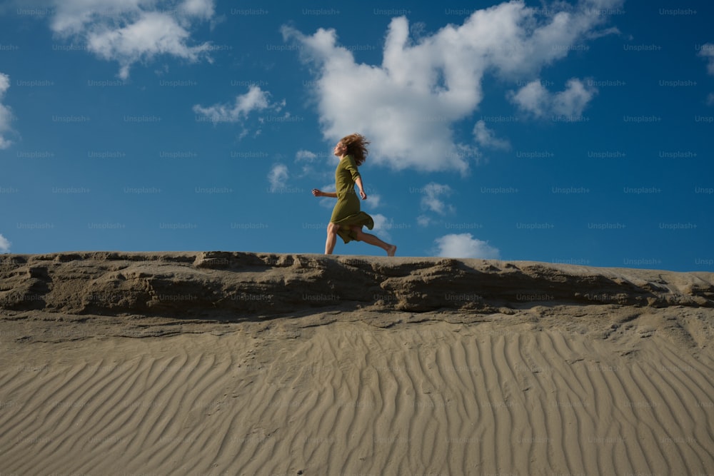Uma mulher em um vestido verde está correndo na areia