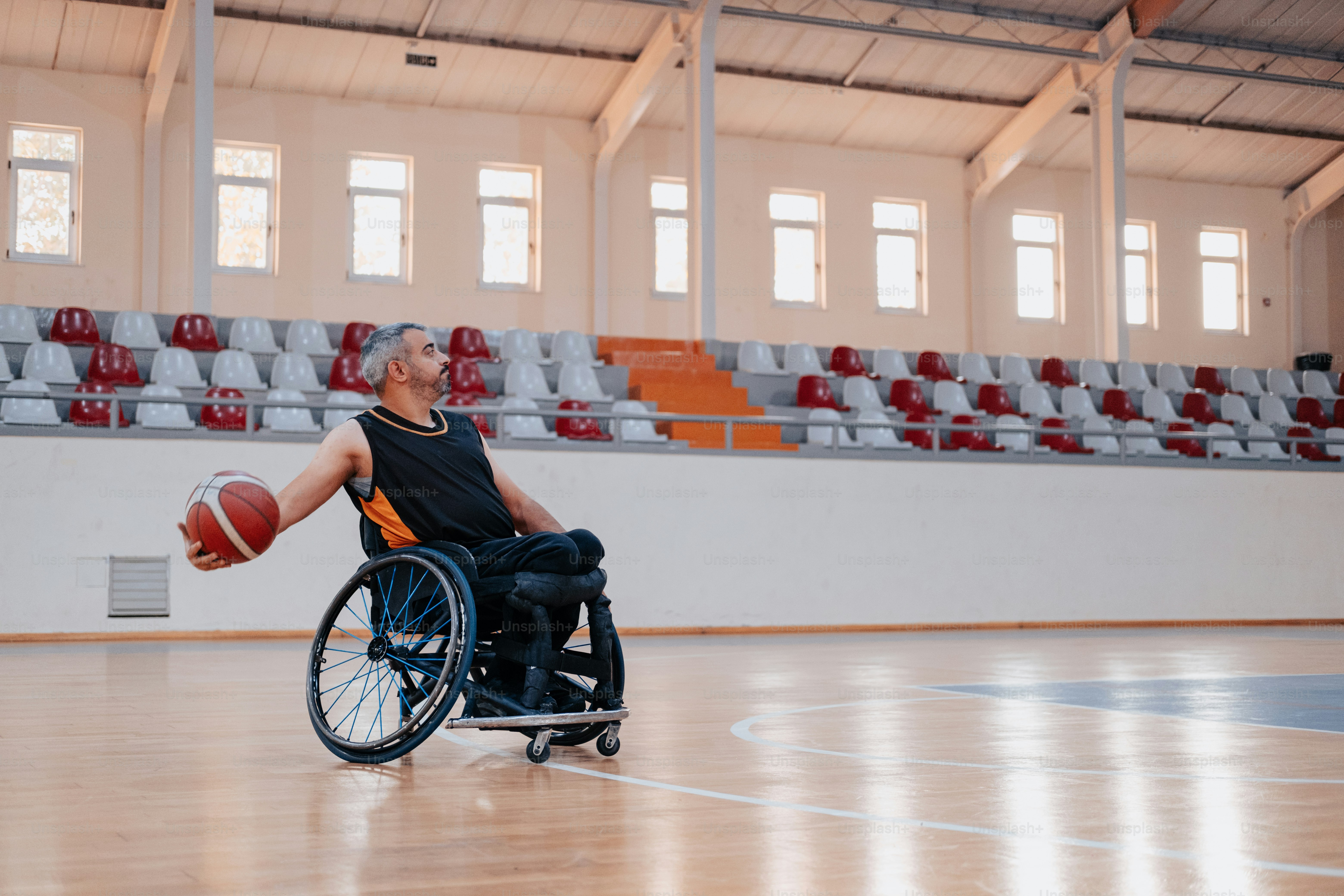 Un hombre en una silla de ruedas sosteniendo una pelota de baloncesto