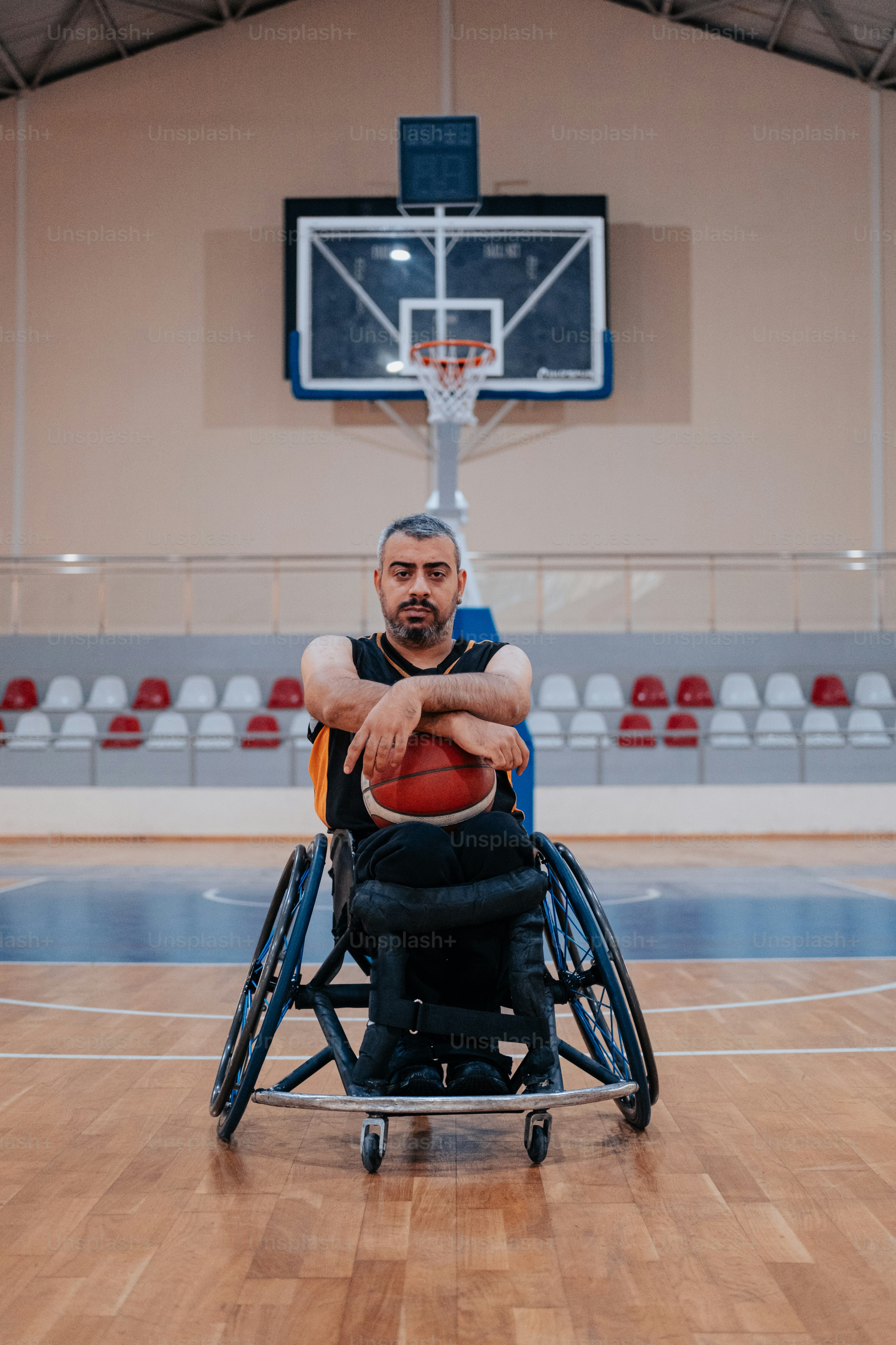 Un hombre en silla de ruedas sosteniendo una pelota de baloncesto
