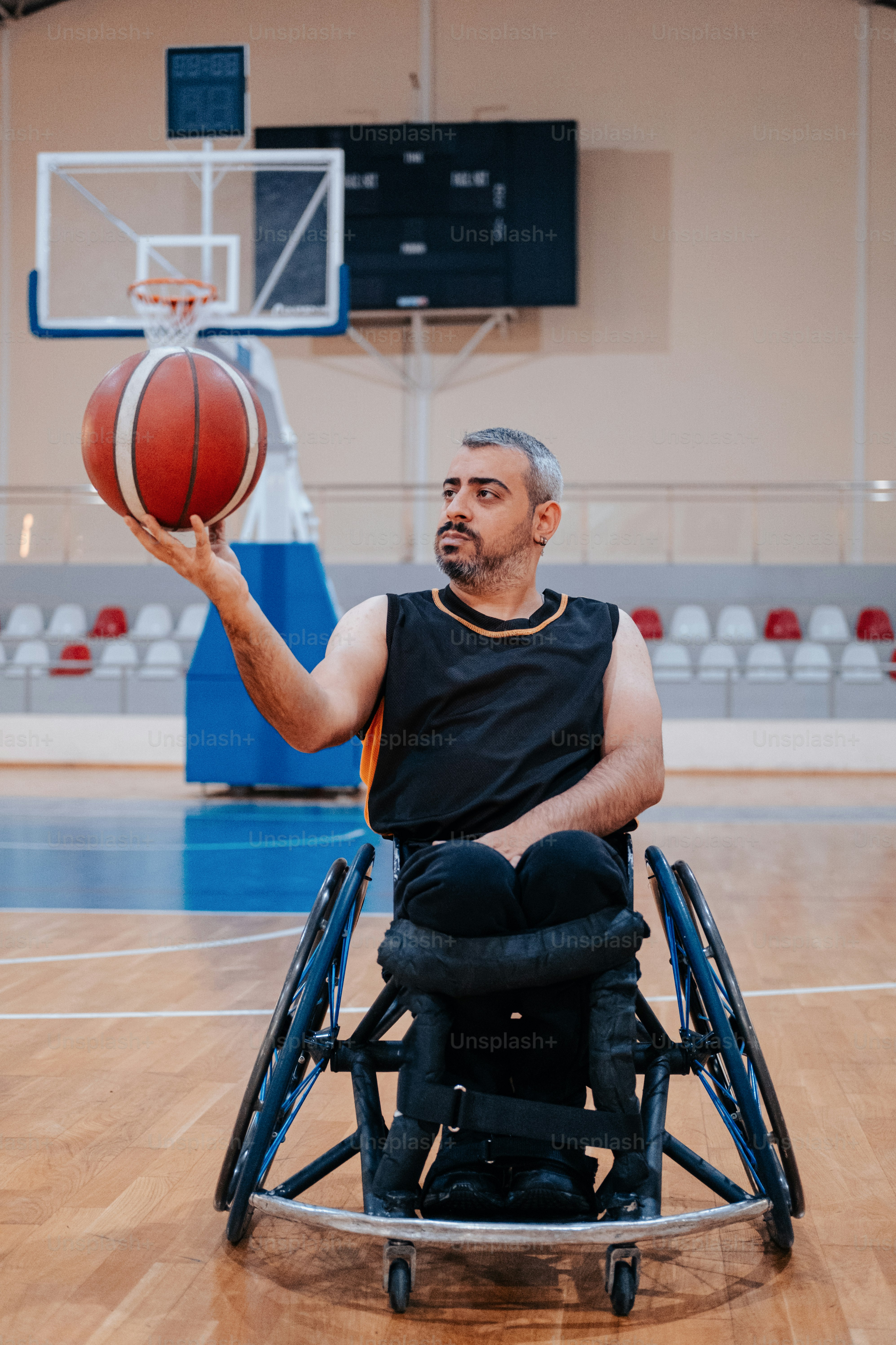 Un hombre en silla de ruedas sosteniendo una pelota de baloncesto