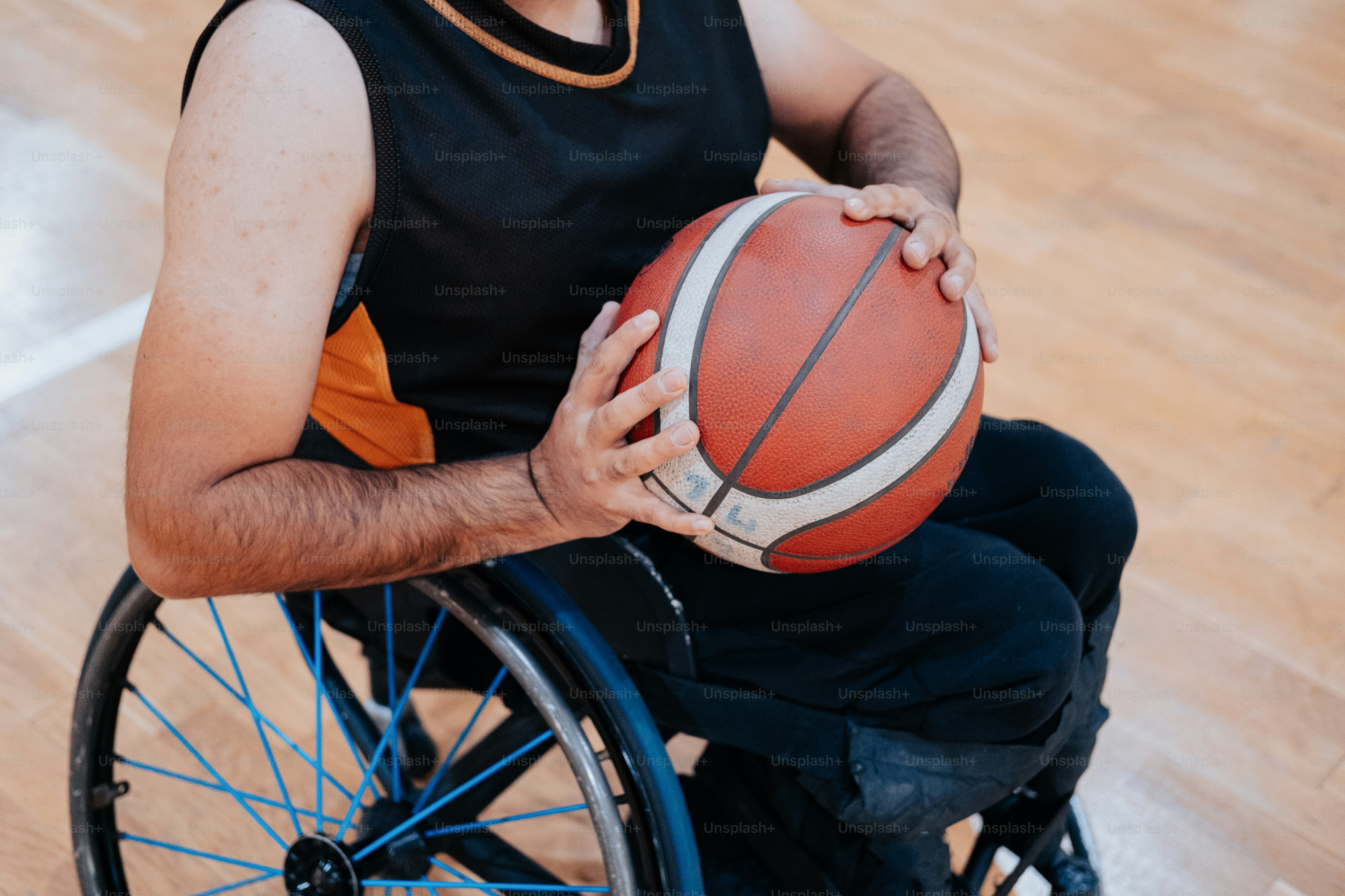 Un hombre en silla de ruedas sosteniendo una pelota de baloncesto