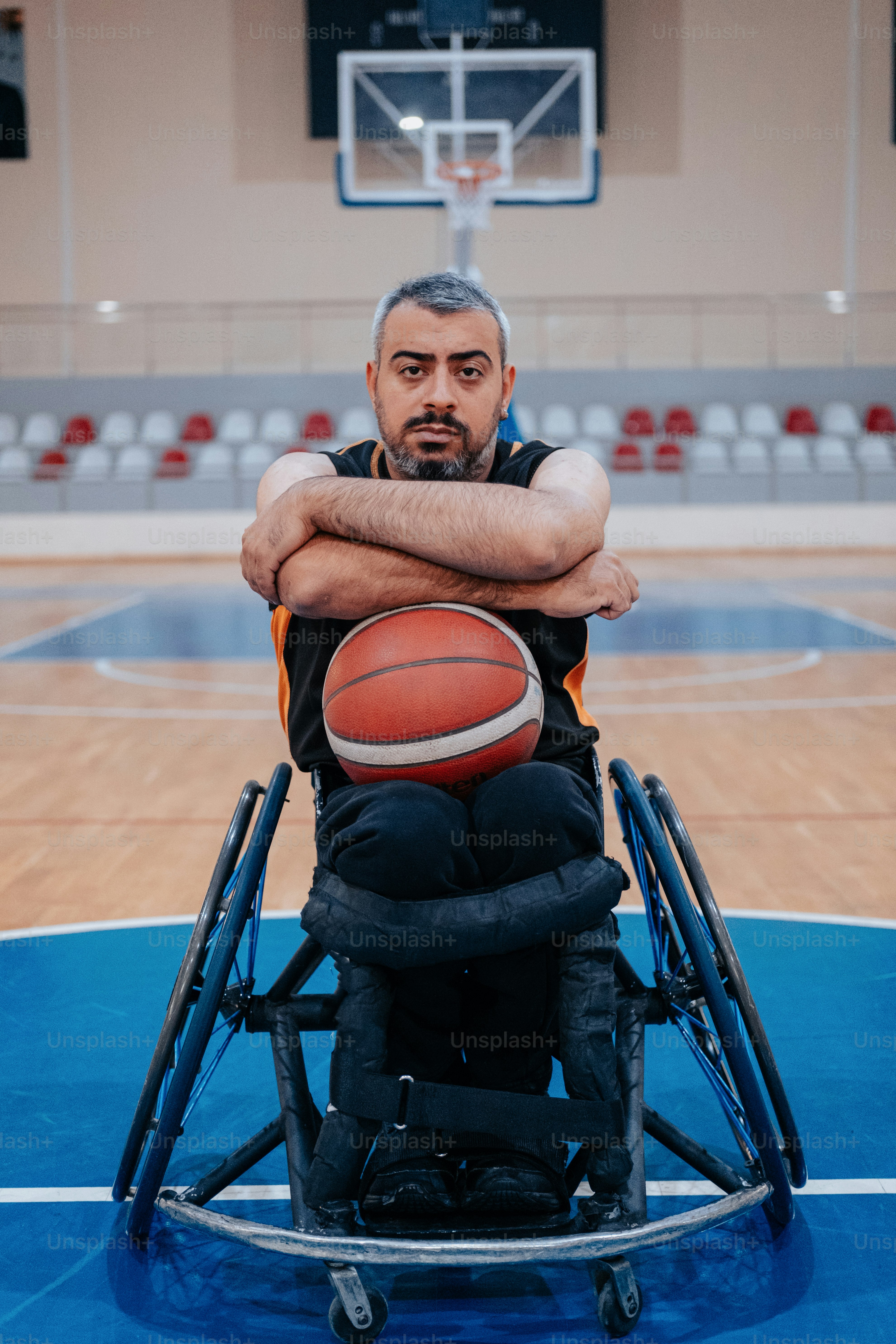 Un hombre en silla de ruedas sosteniendo una pelota de baloncesto