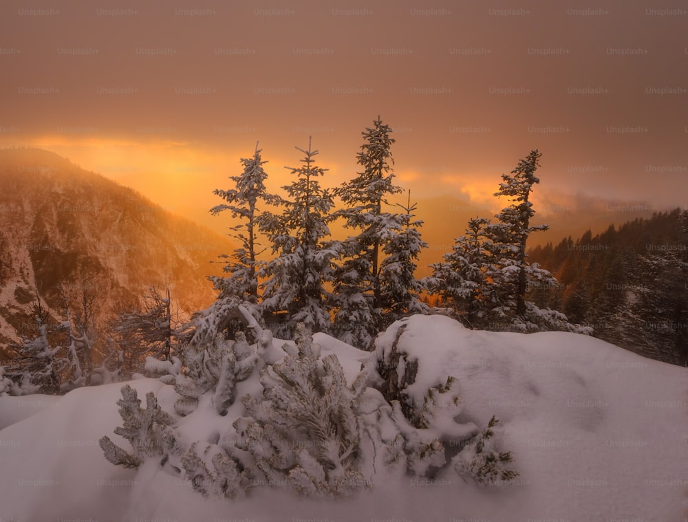 the sun is setting over a snowy mountain