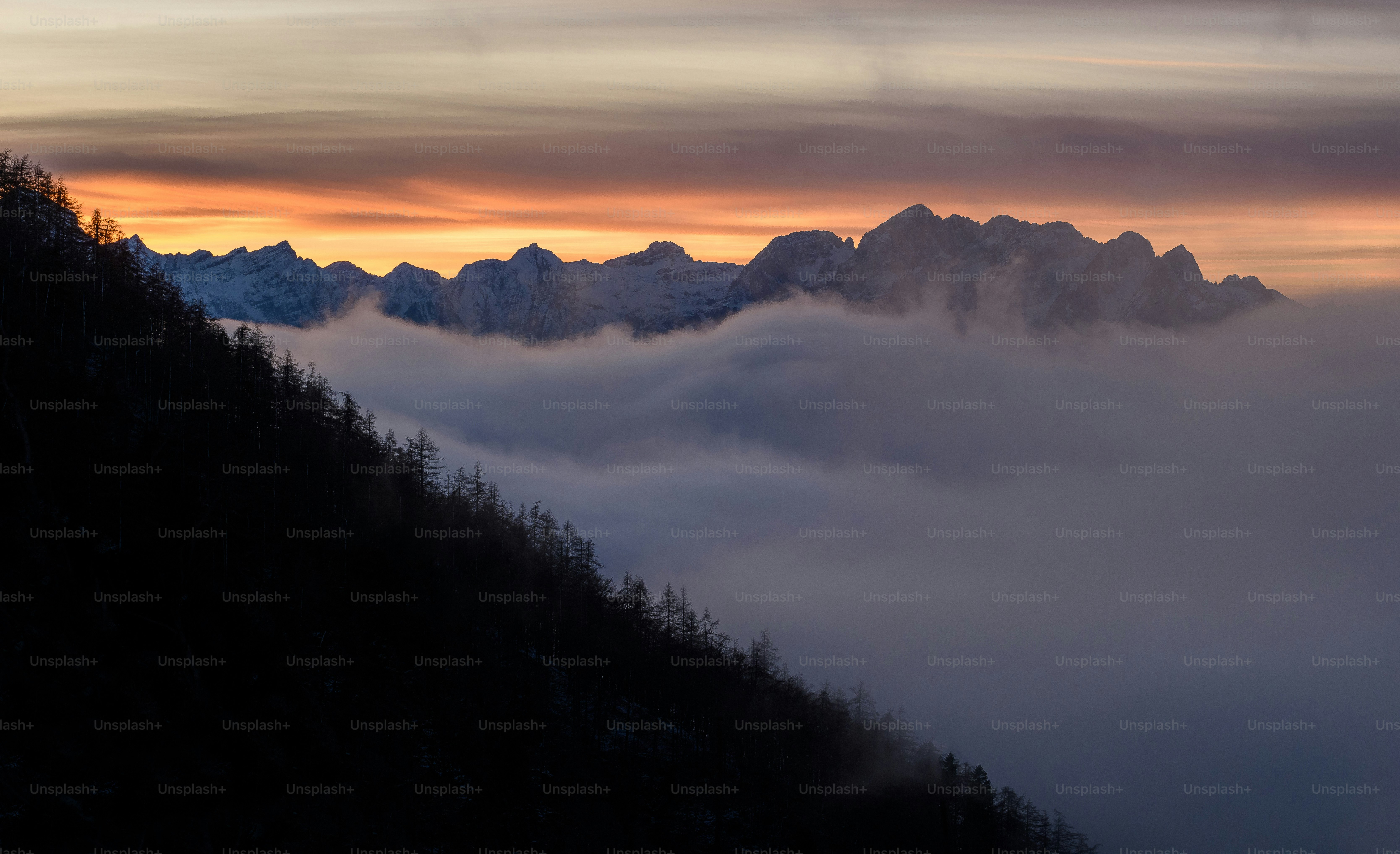 a mountain covered in fog and clouds at sunset