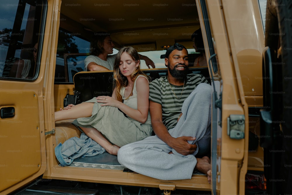 a man and a woman sitting in the back of a truck