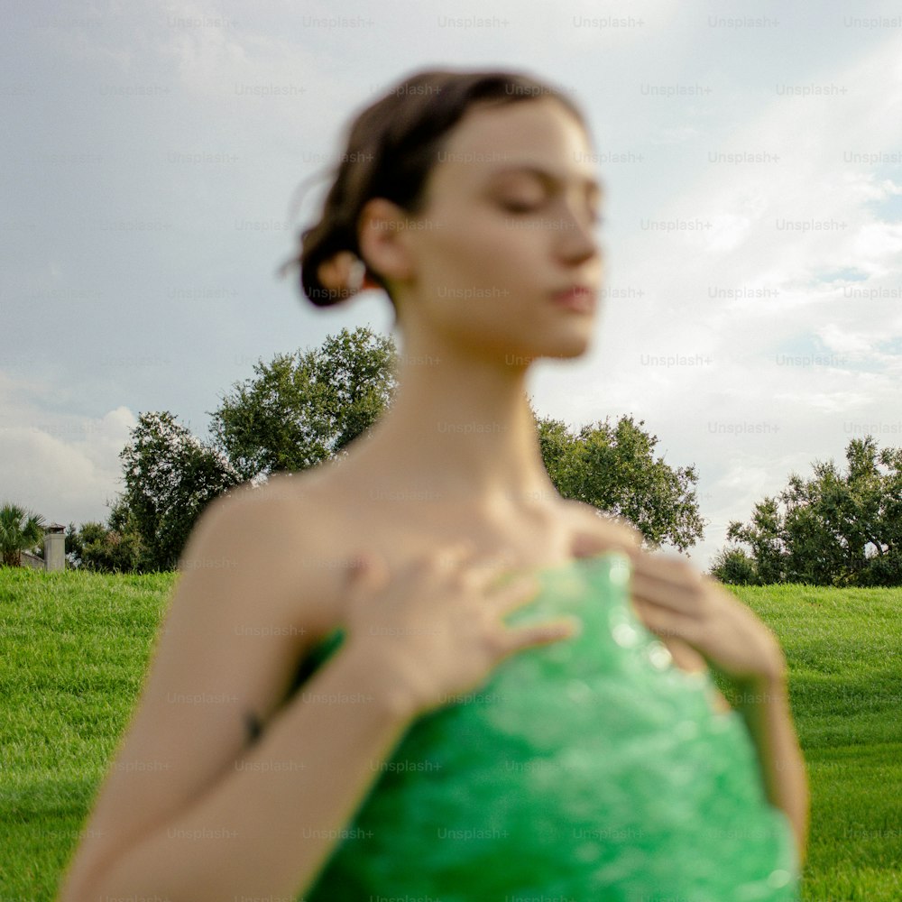 uma mulher em um vestido verde em pé em um campo