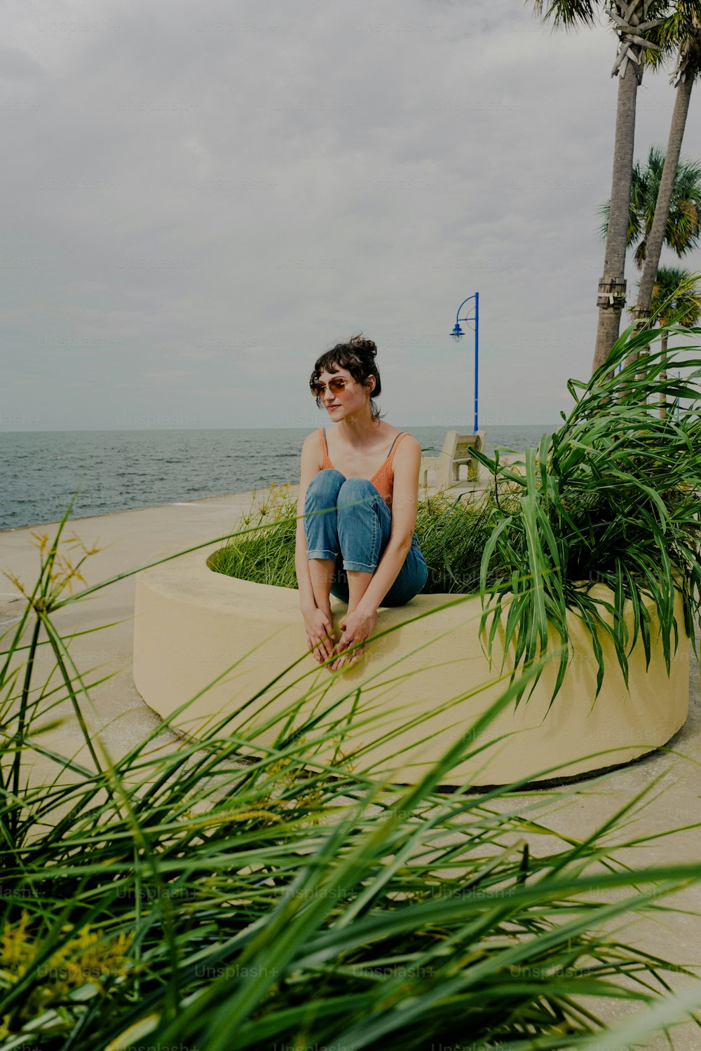 a woman sitting on a bench near the ocean