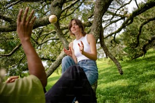 uma mulher está jogando uma bola em uma árvore