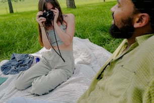 a woman sitting on a blanket holding a camera