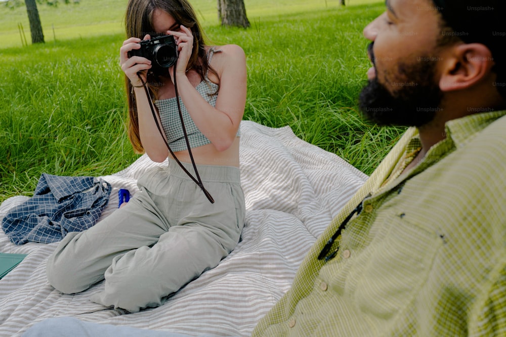 a woman sitting on a blanket holding a camera