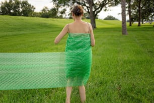 a woman in a green dress is walking through the grass