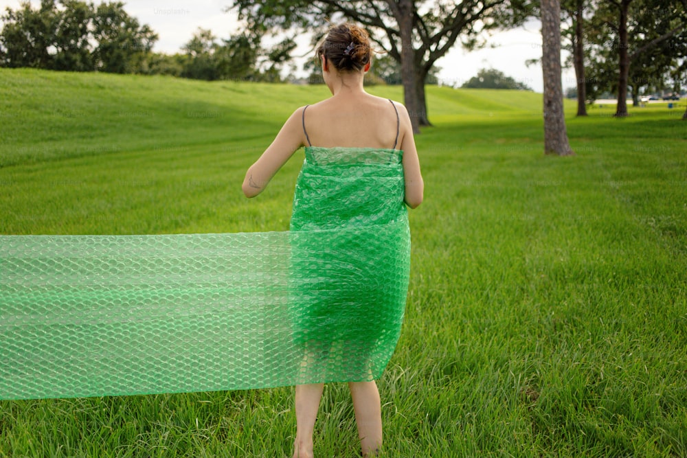 緑のドレスを着た女性が草の中を歩いている