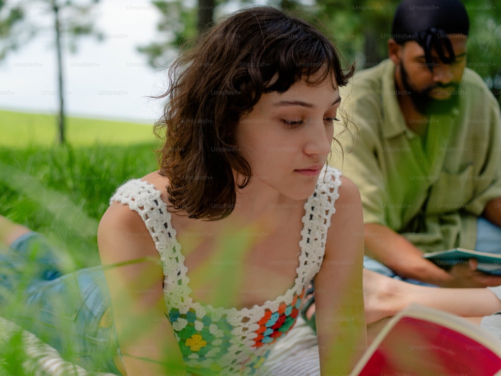 a woman sitting in the grass reading a book