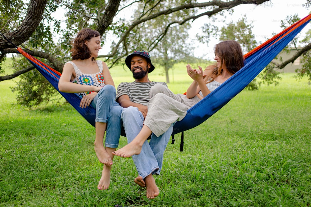 a man and two women sitting in a hammock