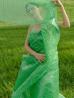 a woman in a green dress is holding a piece of plastic