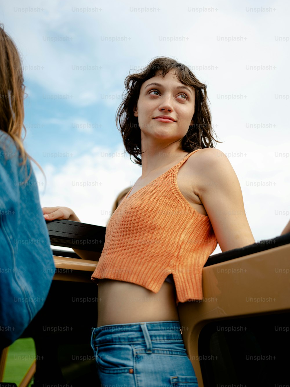 a woman in an orange top standing next to a tv
