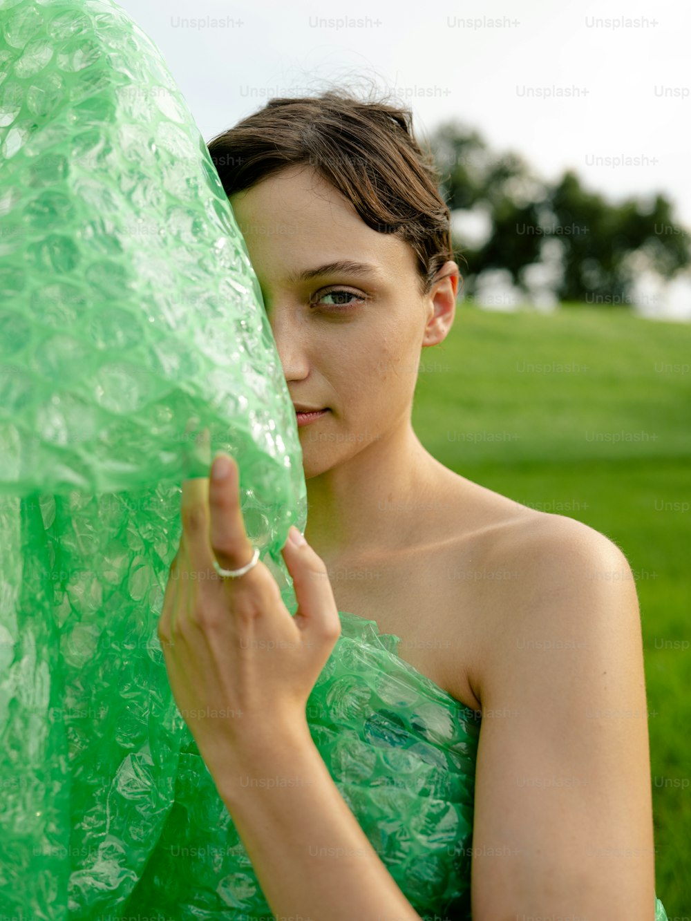 Una mujer con un vestido verde sosteniendo un gran objeto verde