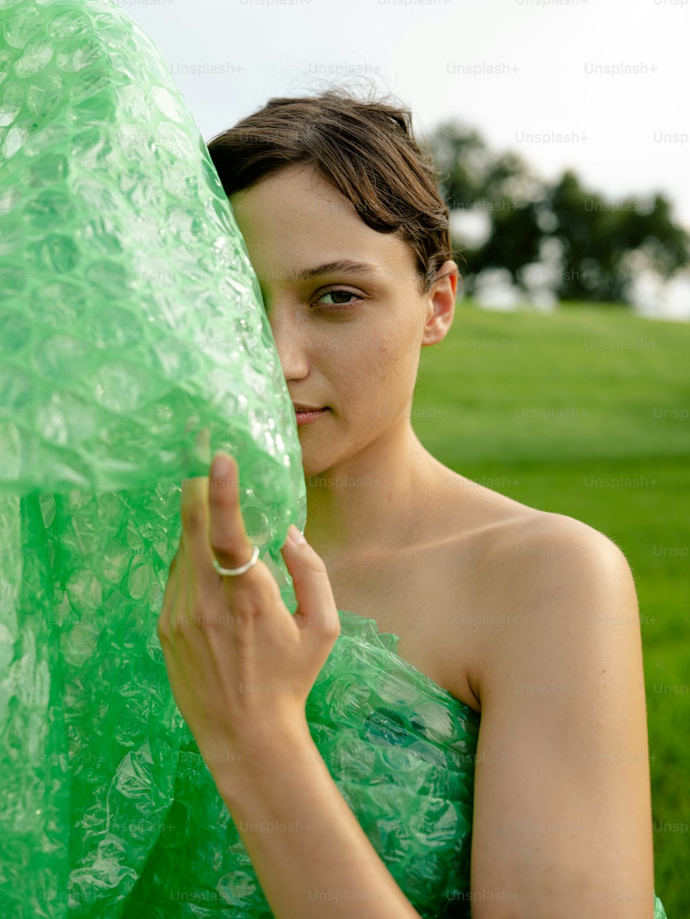a woman in a green dress holding a large green object