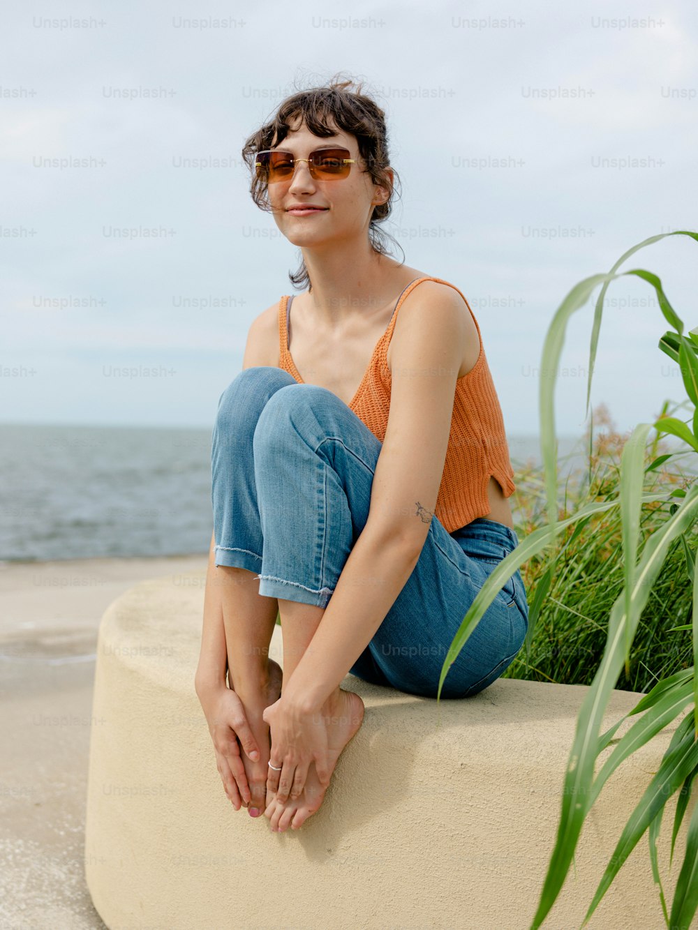 a woman sitting on top of a cement block near the ocean