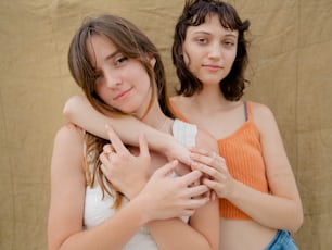 two young girls hugging each other in front of a tan background
