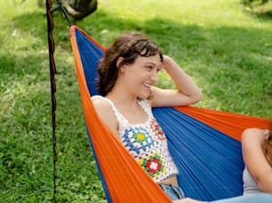 a woman sitting in a hammock with another woman