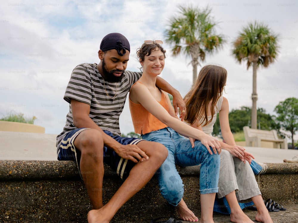 a man and two women sitting on a stone wall