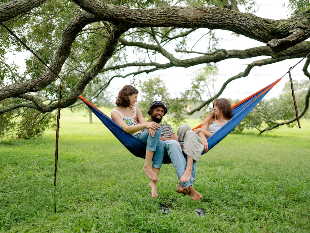 a man and two women sitting in a hammock