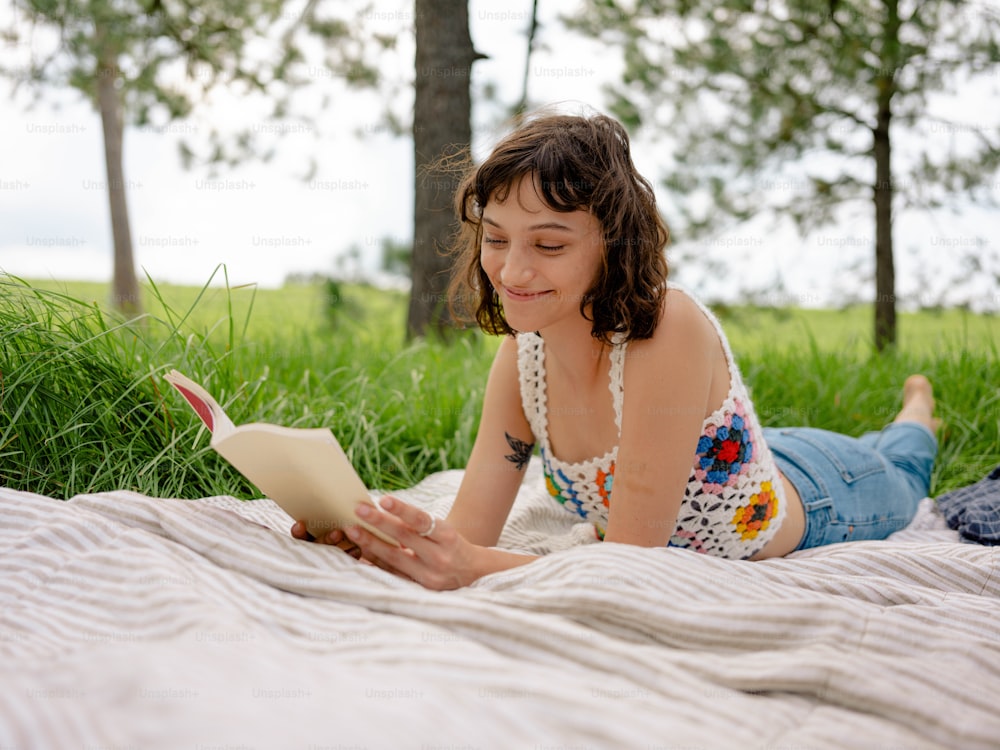 a girl laying on a blanket reading a book
