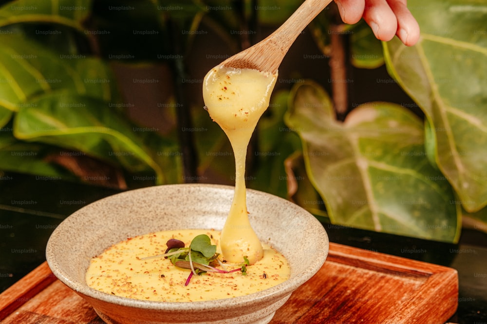 a wooden spoon is pouring sauce into a bowl