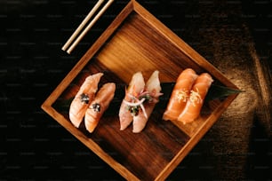 un piatto di legno condito con sushi e bacchette