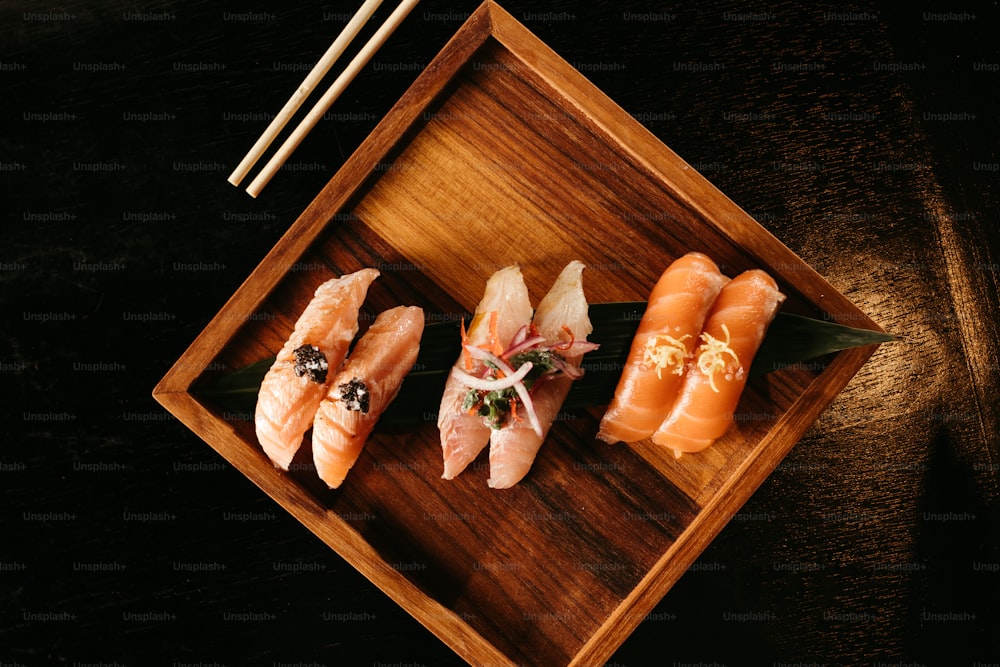 um prato de madeira coberto com sushi e pauzinhos