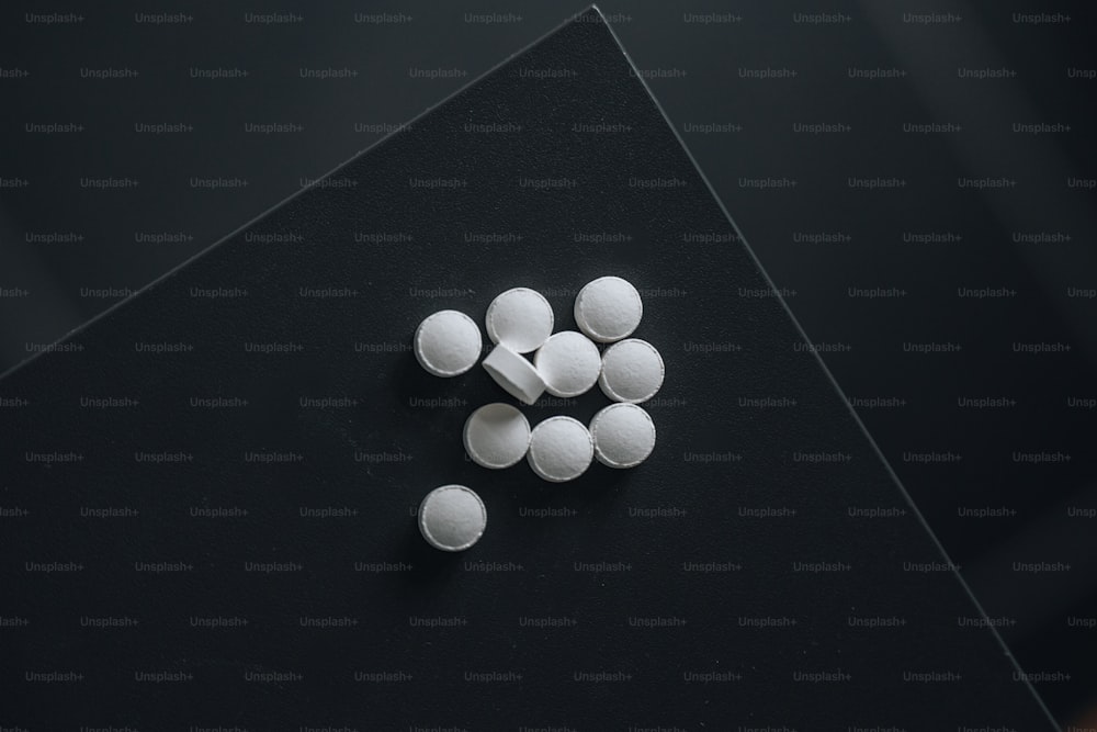 a pile of white pills sitting on top of a black table